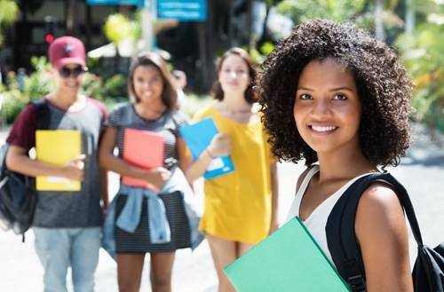 A girl holding a binder standing in front of a group of pens.